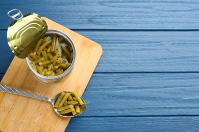 Canned green beans on blue wooden table, top view. Space for text