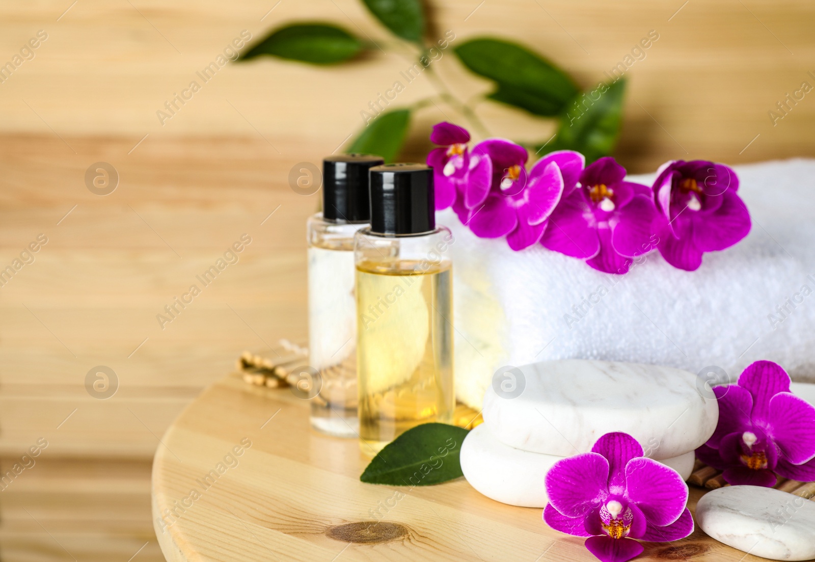 Photo of Composition with spa stones and orchid flowers on wooden table. Space for text