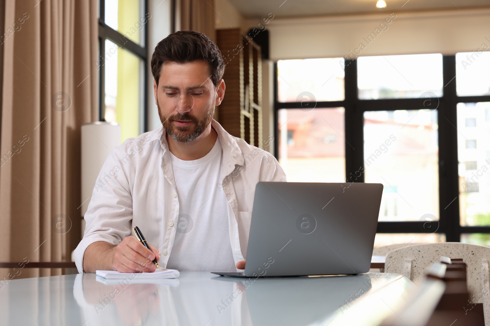 Photo of Man working with laptop at table in cafe