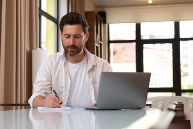 Man working with laptop at table in cafe