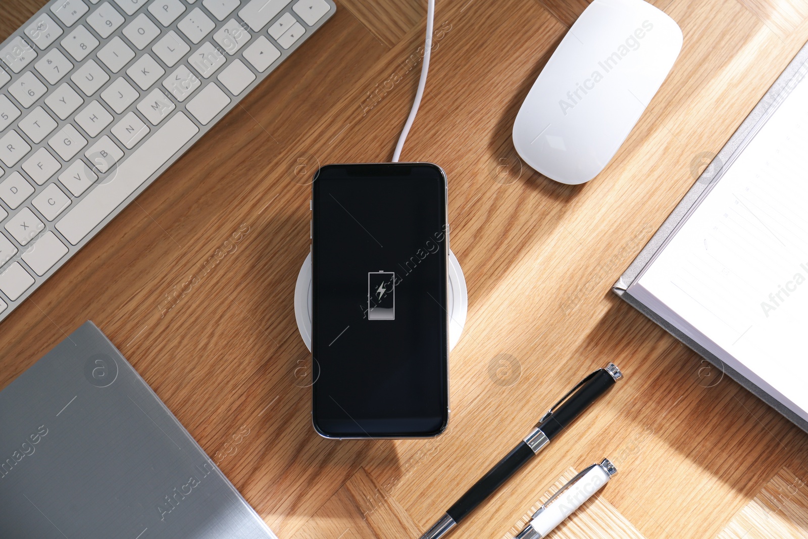 Photo of Smartphone charging with wireless pad, flat lay. Modern workplace