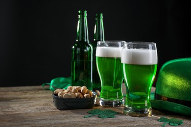 Photo of St. Patrick's day party. Green beer, nuts, leprechaun hat and decorative clover leaves on wooden table. Space for text
