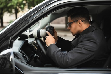 Photo of Private detective with camera spying from car