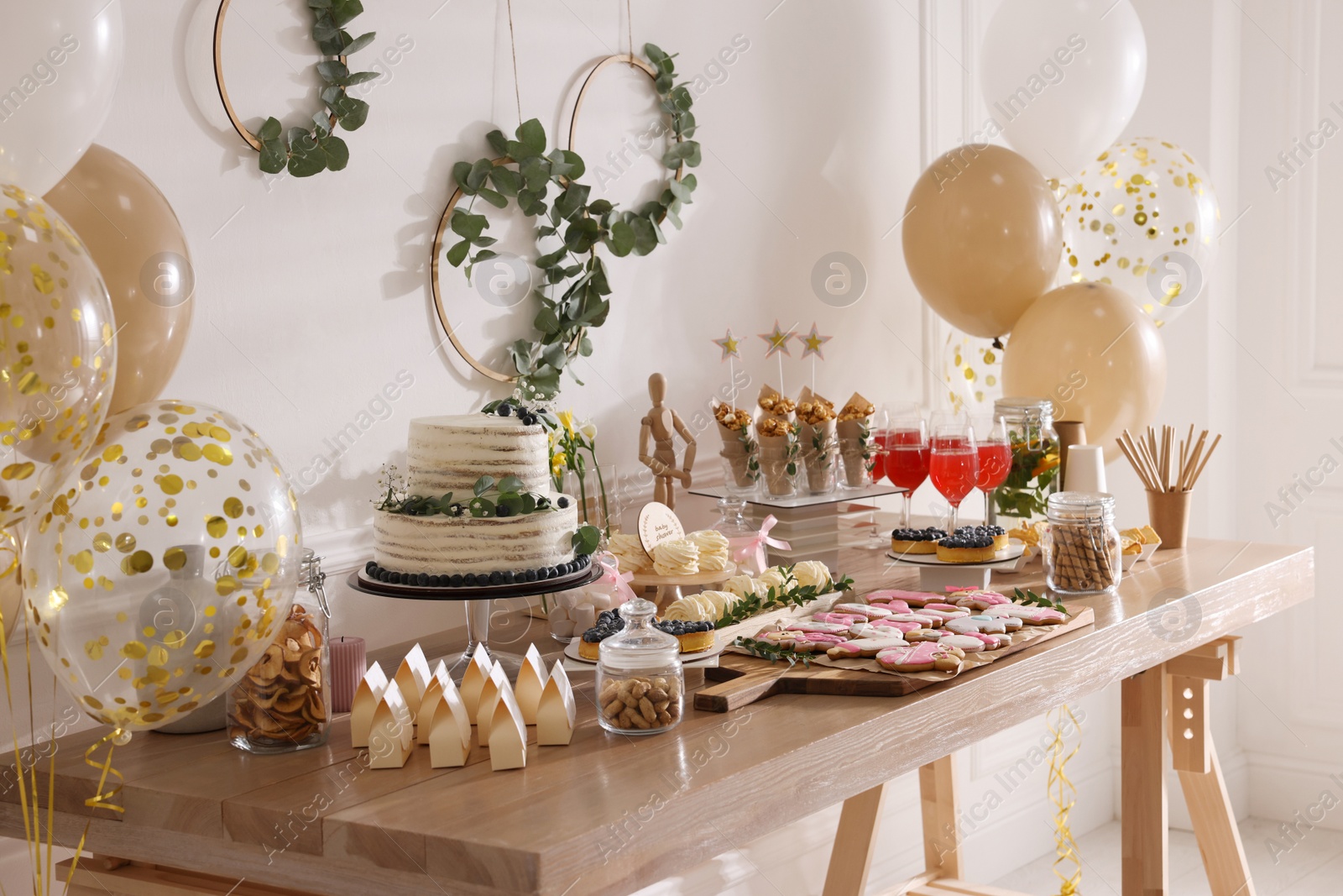 Photo of Baby shower party. Different delicious treats on wooden table indoors