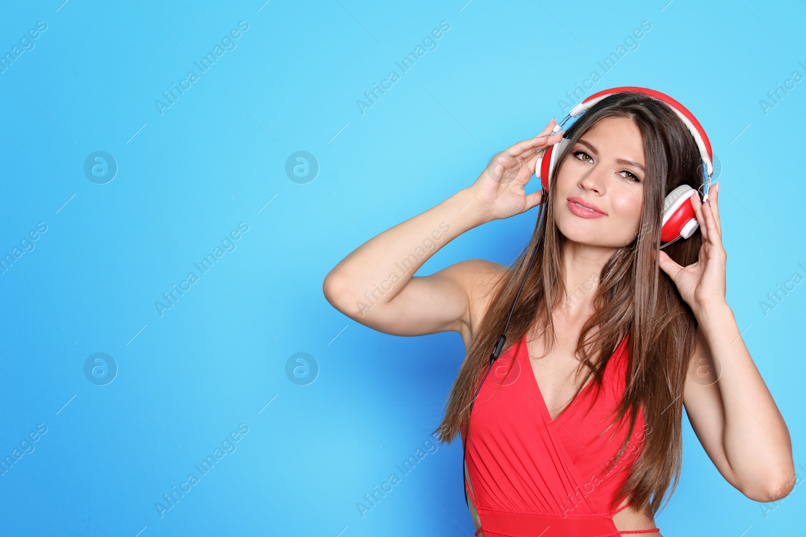 Photo of Sexy young woman in bikini listening to music on color background