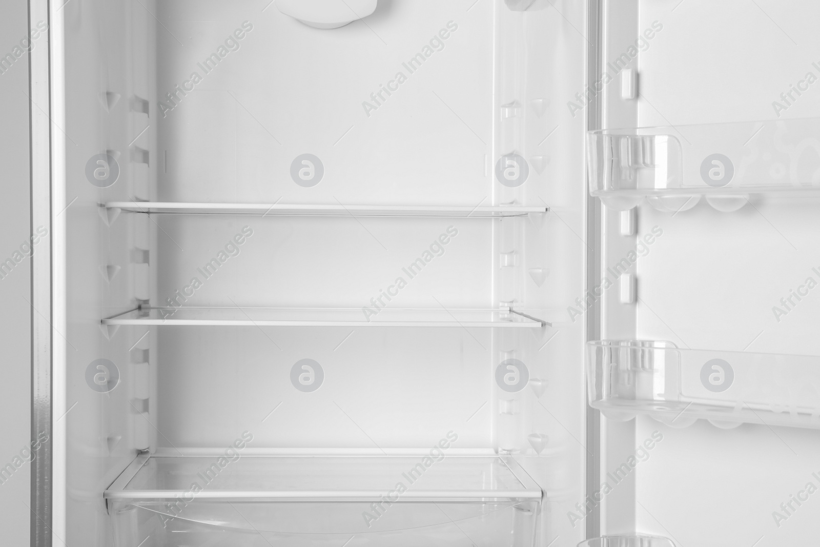 Photo of Modern open refrigerator with empty shelves, closeup