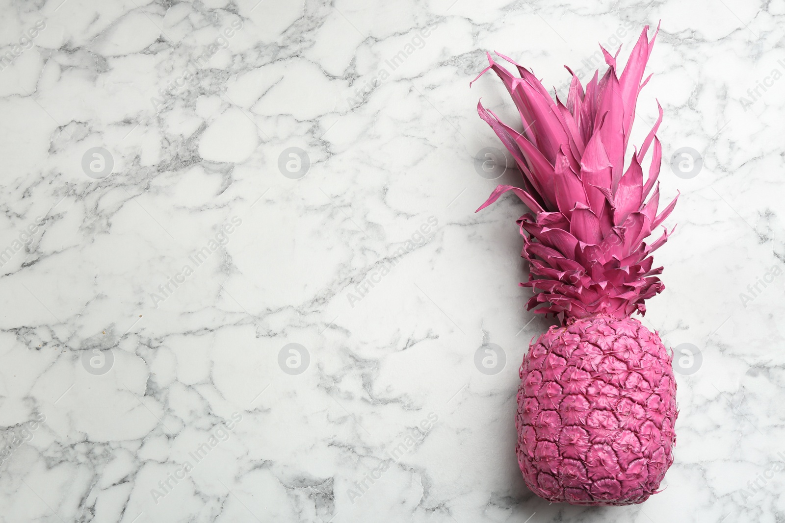 Photo of Pink pineapple on white marble background, top view with space for text. Creative concept