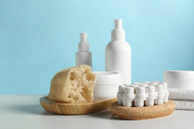 Different bath accessories on white table against light blue background