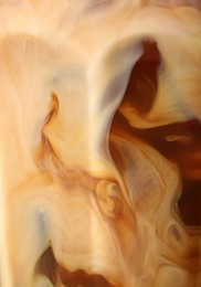 Photo of Glass of coffee with milk and ice cubes on blurred background, closeup
