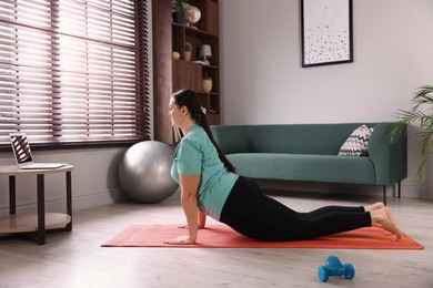 Photo of Overweight woman doing exercise on yoga mat at home