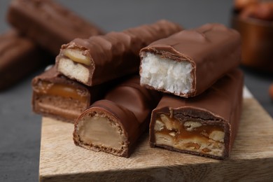 Photo of Pieces of different tasty chocolate bars on wooden board, closeup