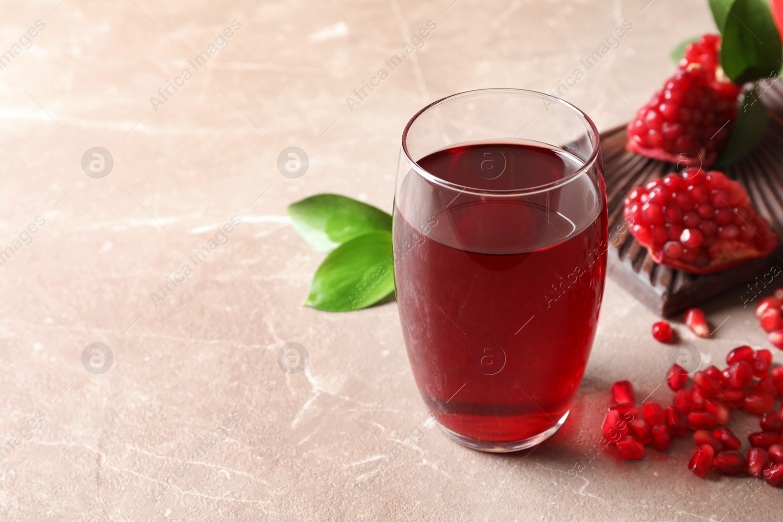 Photo of Composition with glass of fresh pomegranate juice on table. Space for text