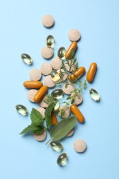 Different pills and herbs on light blue background, flat lay. Dietary supplements