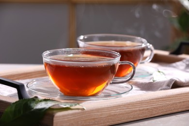 Aromatic hot tea in glass cups on light grey table indoors, closeup