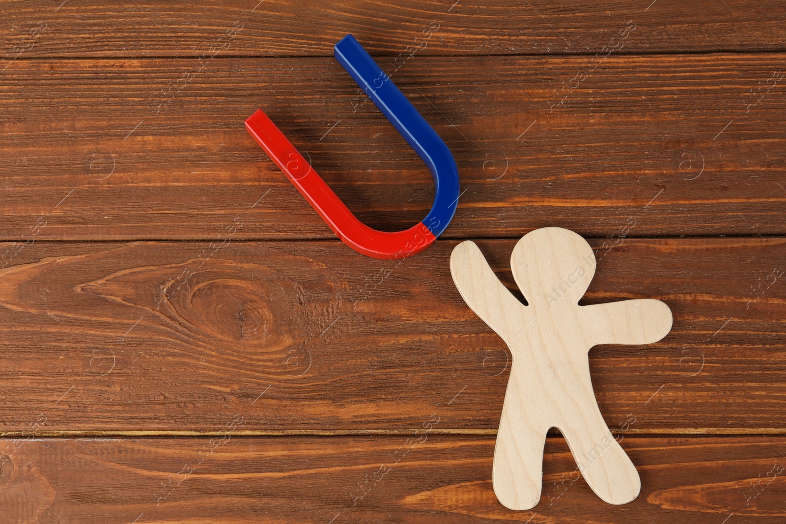 Photo of Magnet and paper person on wooden table, flat lay