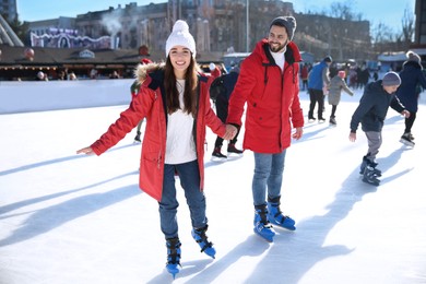 Lovely couple spending time together at outdoor ice skating rink