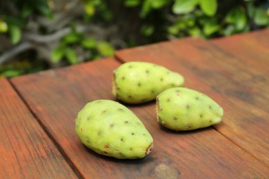 Tasty prickly pear fruits on wooden table outdoors