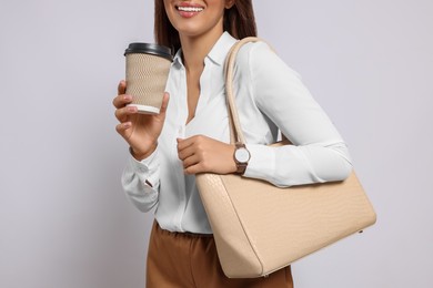 Photo of Young woman with stylish bag and cup of hot drink on white background, closeup
