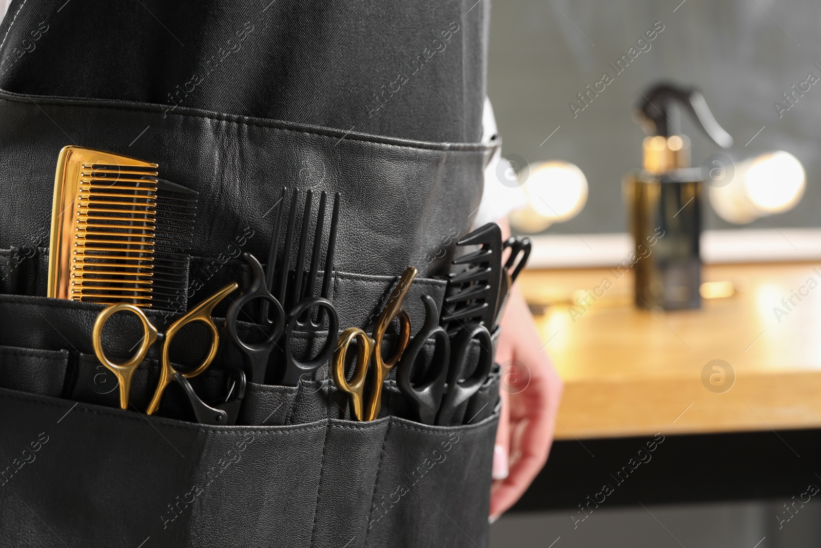 Photo of Hairstylist with professional tools in waist pouch in salon, closeup