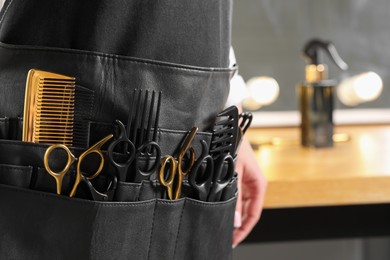 Hairstylist with professional tools in waist pouch in salon, closeup