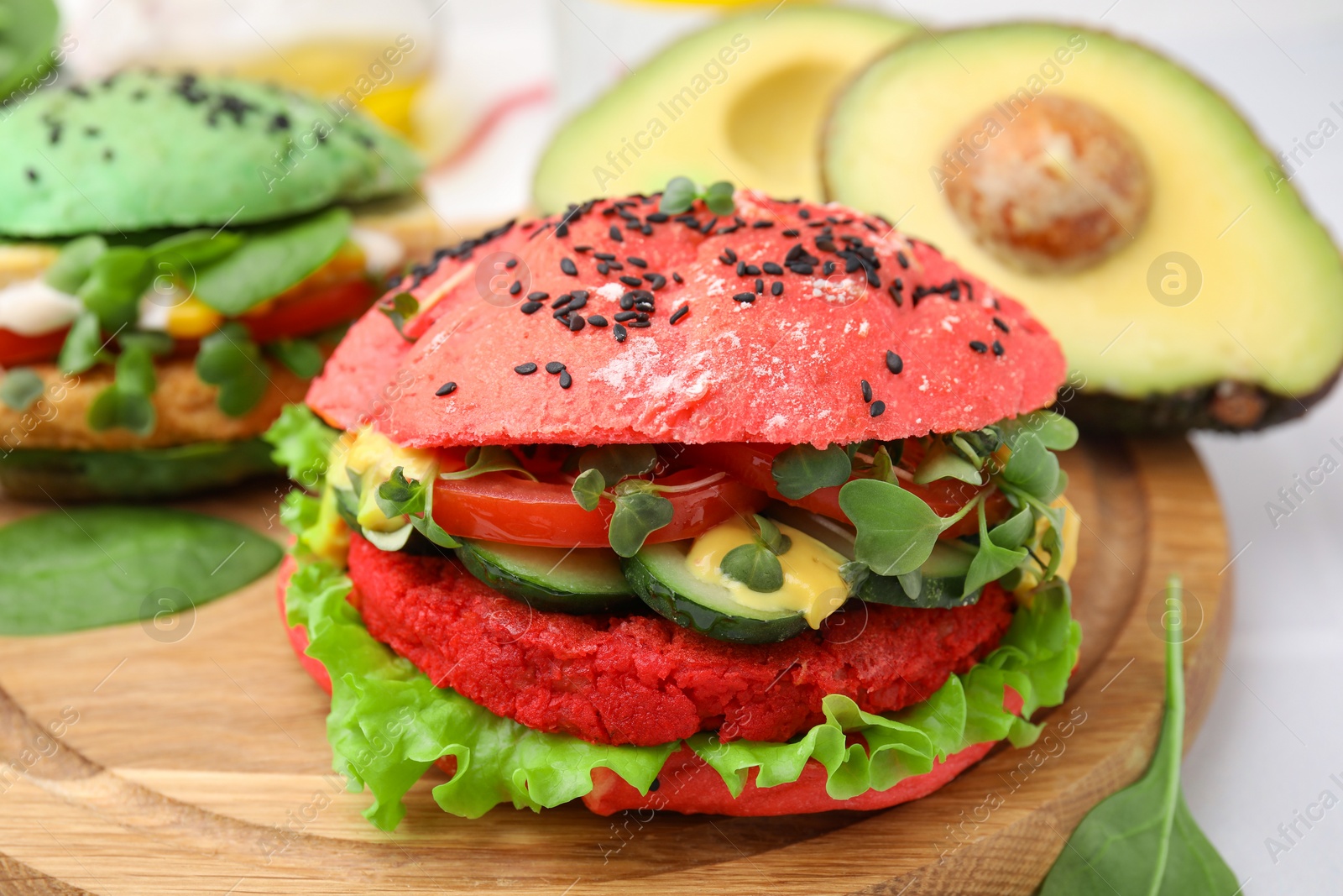 Photo of Tasty pink vegan burger with vegetables, patty and microgreens on white table, closeup