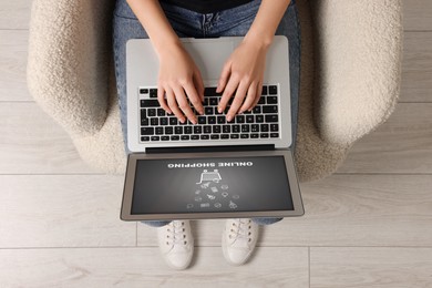 Woman using laptop for online shopping in armchair indoors, top view