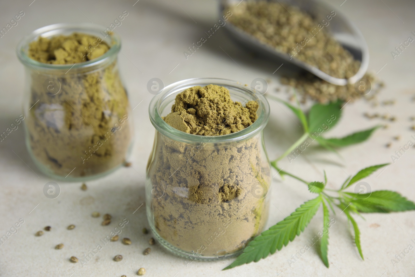 Photo of Hemp protein powder, seeds and fresh leaves on light grey table, closeup