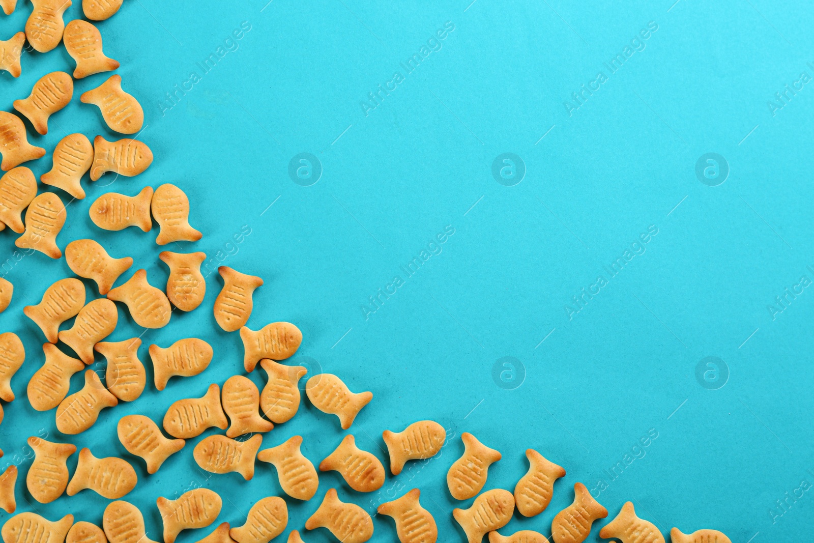Photo of Delicious goldfish crackers on blue background, flat lay. Space for text