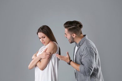 Young couple having argument on grey background. Relationship problems