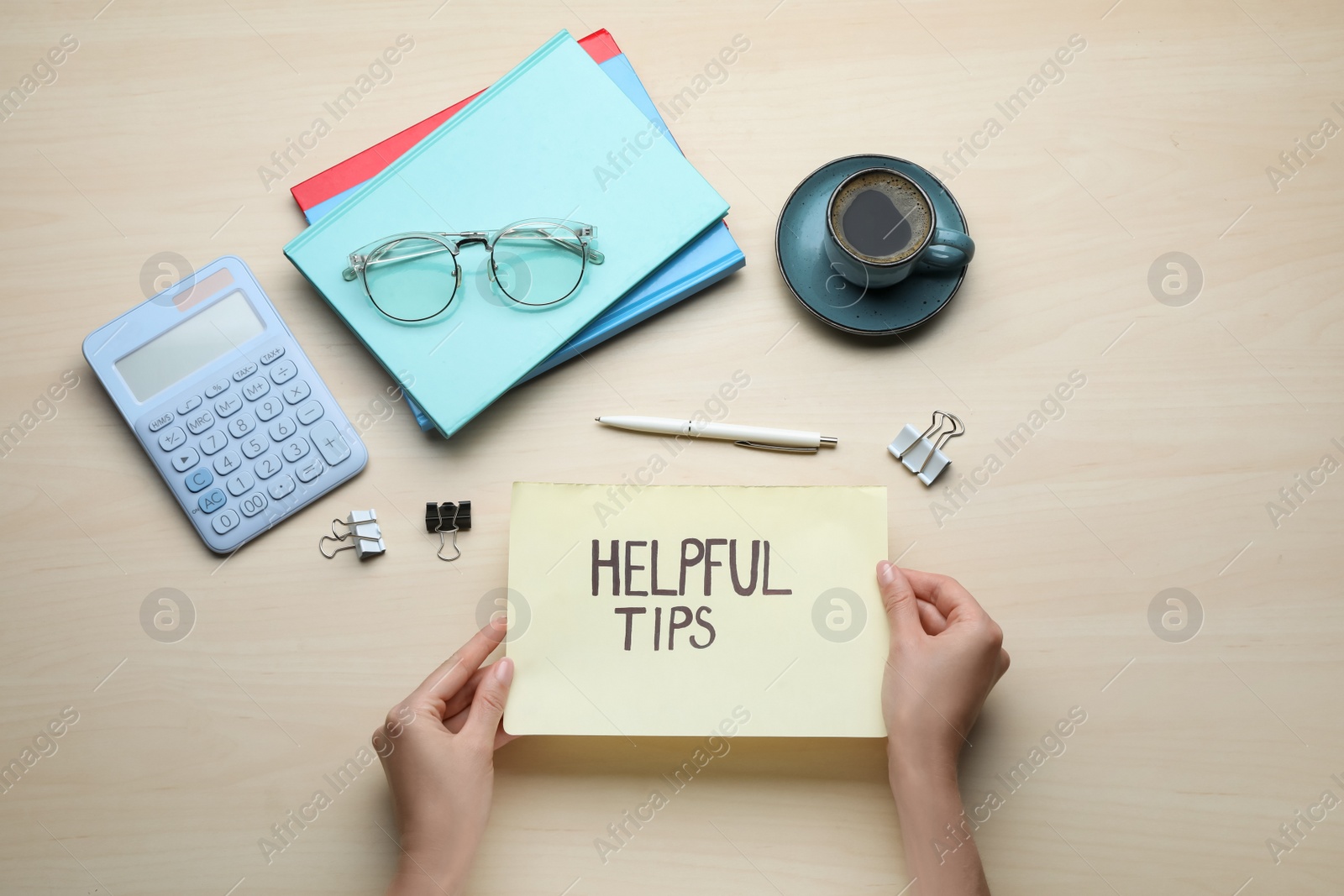 Photo of Woman holding notebook with phrase Helpful Tips at wooden table, top view