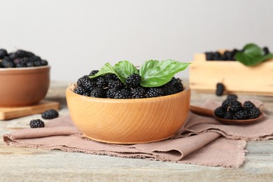 Bowl of delicious ripe black mulberries on wooden table