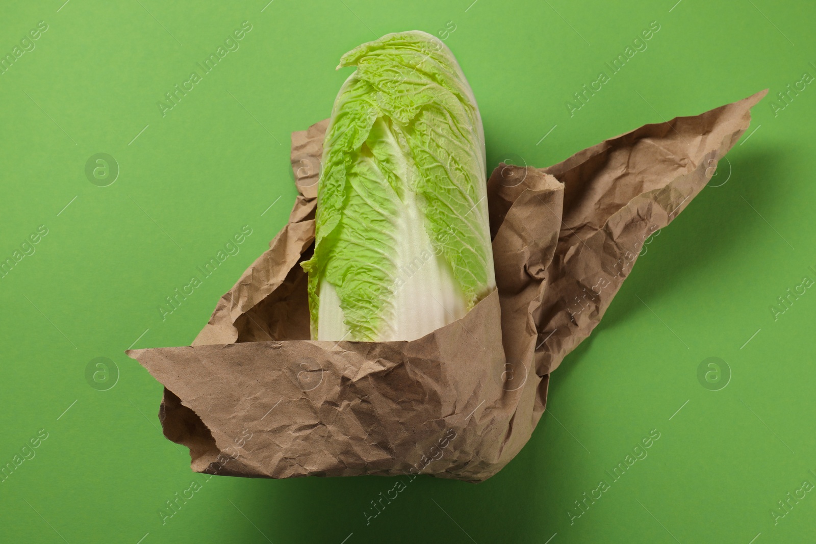 Photo of Whole Chinese cabbage in kraft paper on light green background, top view