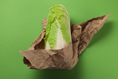 Photo of Whole Chinese cabbage in kraft paper on light green background, top view