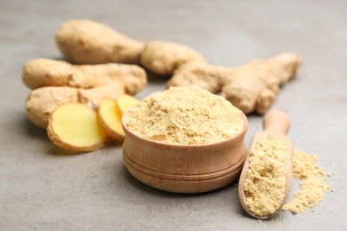 Photo of Dry ginger powder and fresh root on grey table