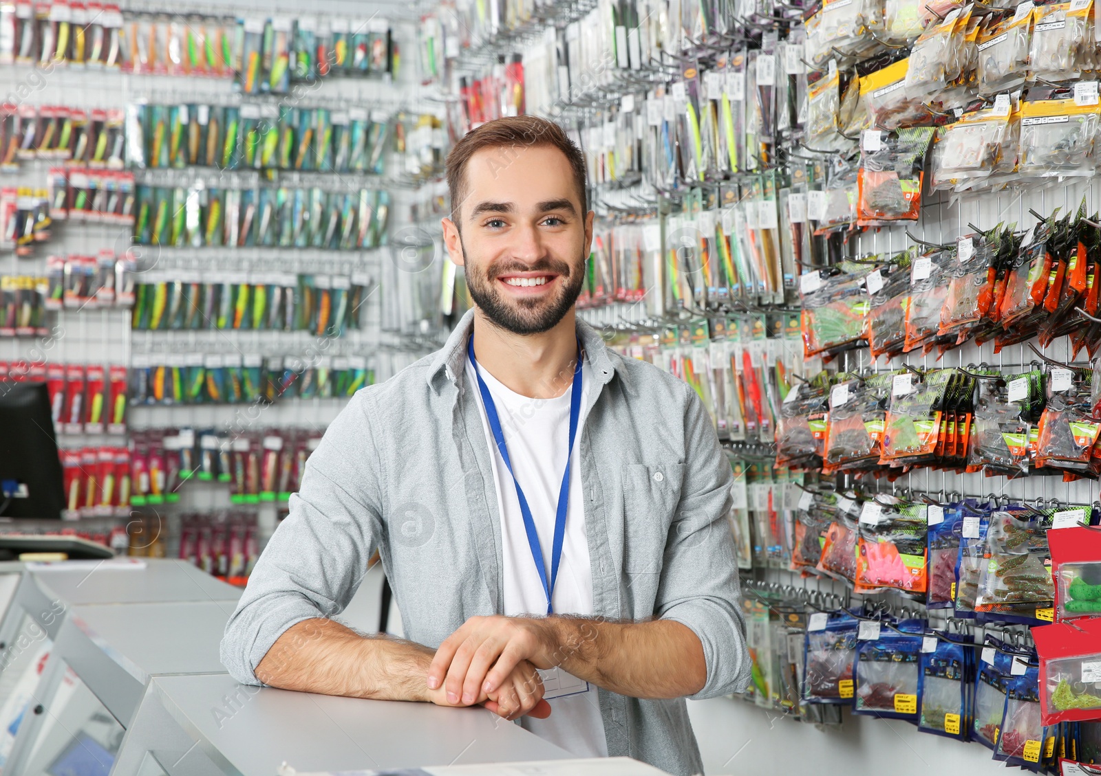 Photo of Salesman standing near showcase with fishing equipment in sports shop