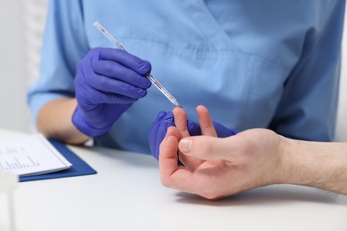 Laboratory testing. Doctor taking blood sample from patient at white table in hospital, closeup