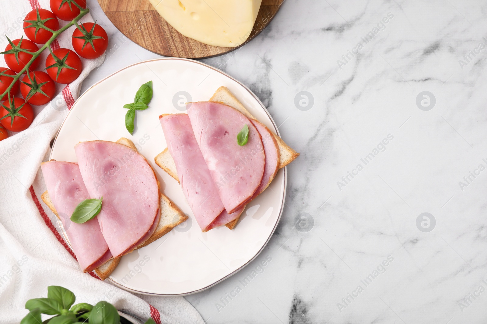 Photo of Delicious sandwiches with ham and products on white marble table, flat lay. Space for text