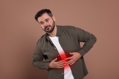 Man suffering from abdominal pain on brown background