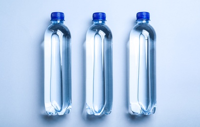 Plastic bottles with water on white background, flat lay