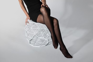 Photo of Woman with beautiful long legs wearing black tights on light background, closeup