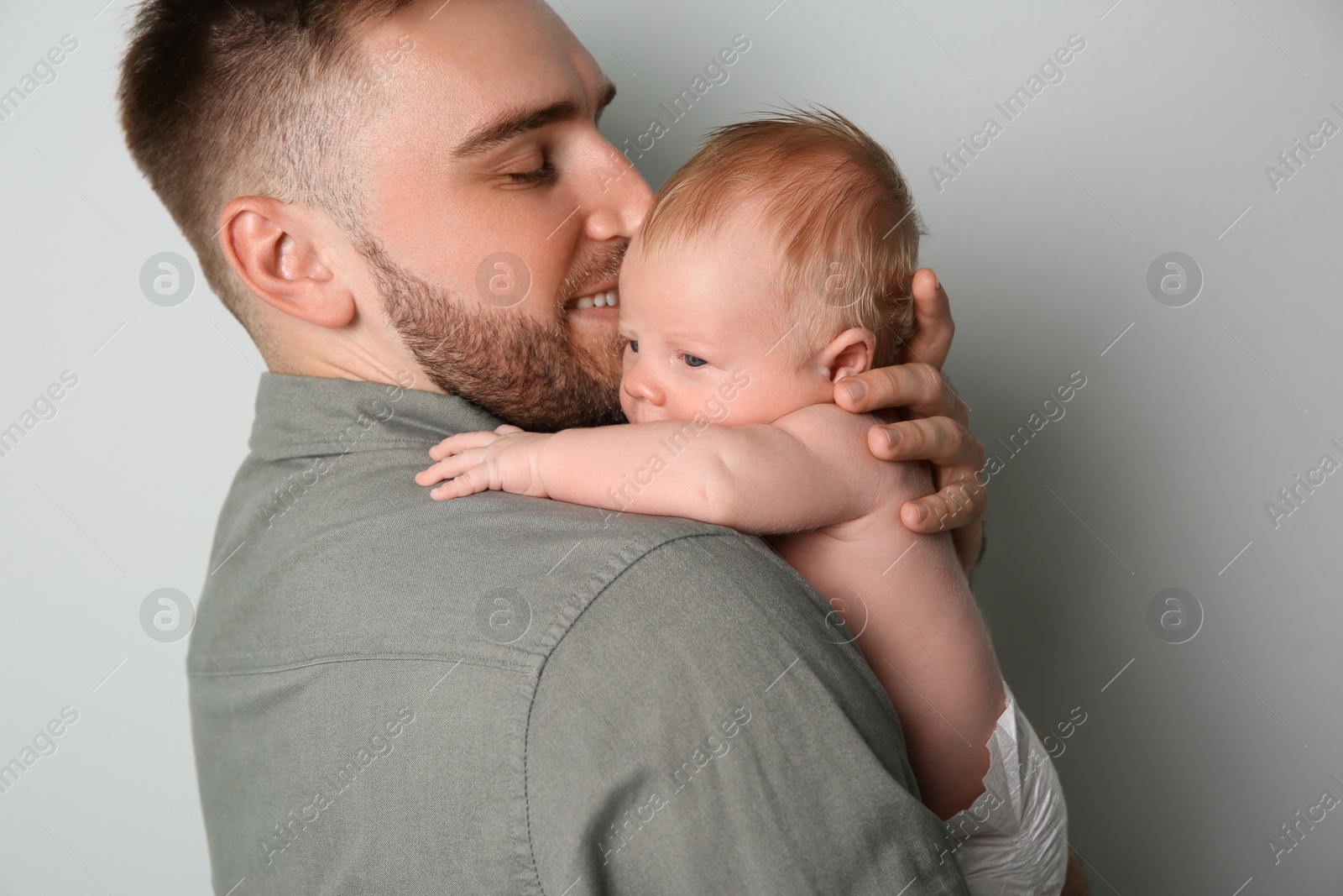 Photo of Father with his newborn son on light grey background