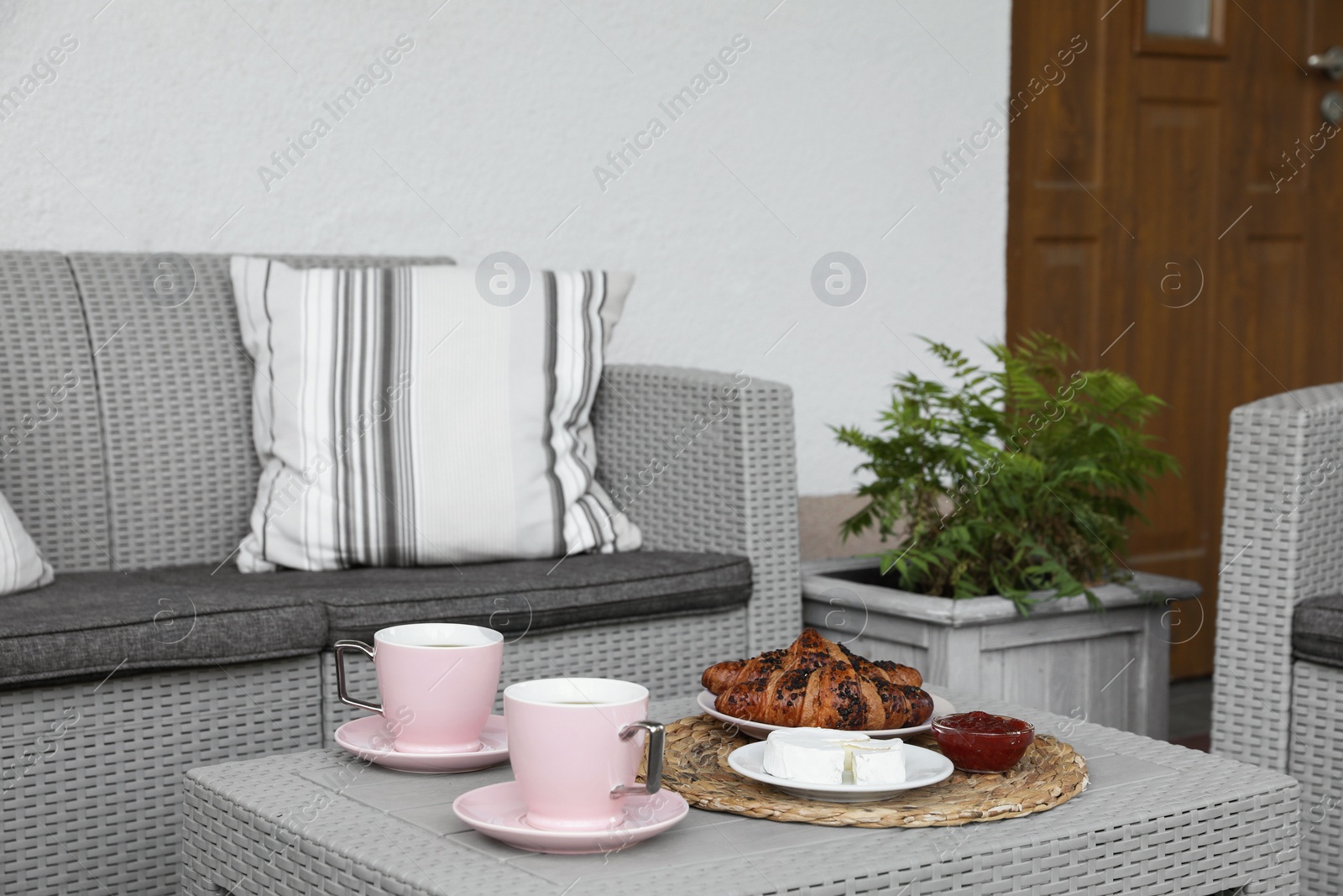 Photo of Outdoor breakfast with tea and croissants on rattan table on terrace