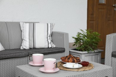 Outdoor breakfast with tea and croissants on rattan table on terrace