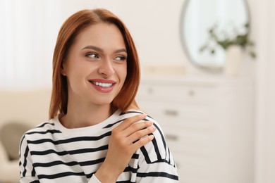 Photo of Portrait of beautiful smiling young woman. Happy lady with red hair at home. Space for text