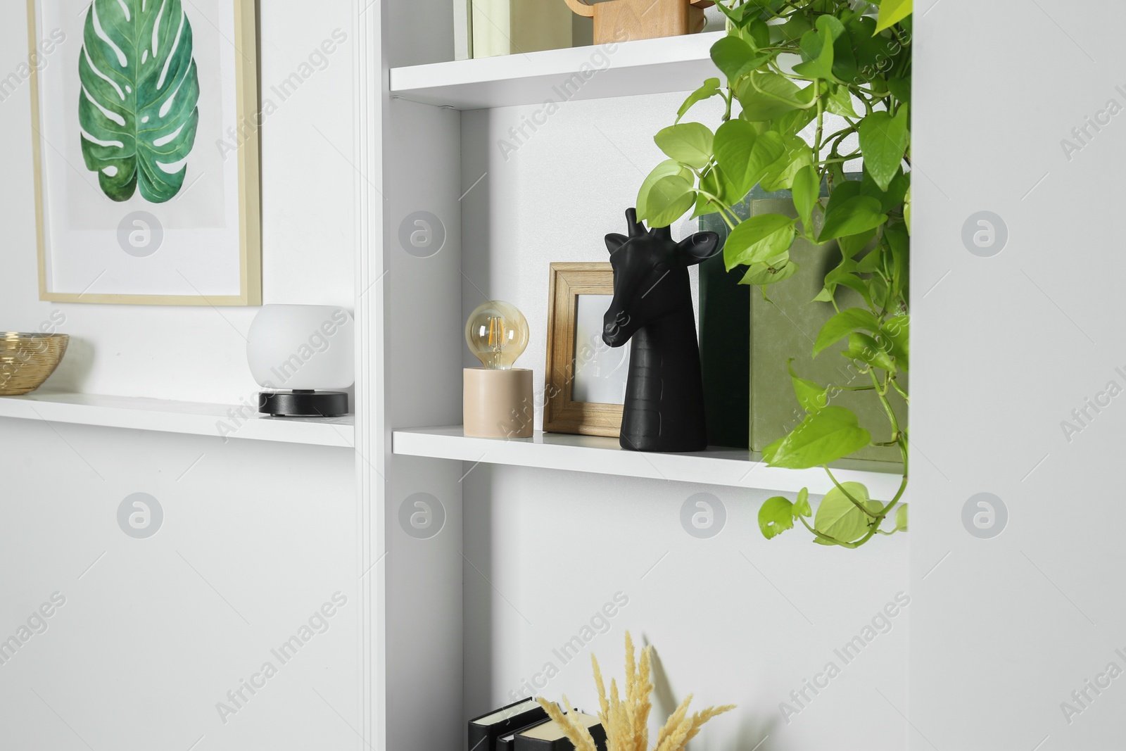 Photo of White shelves with different decor indoors. Interior design