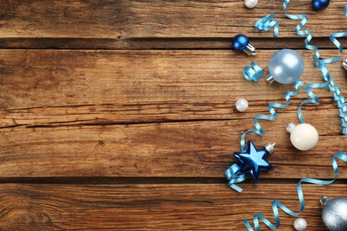 Photo of Blue serpentine streamers and Christmas baubles on wooden background, flat lay. Space for text