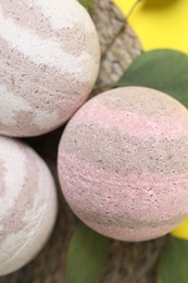 Photo of Bath bombs and leaves on yellow background, flat lay