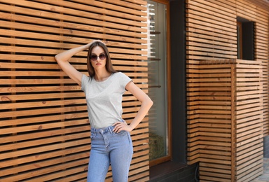 Young woman wearing gray t-shirt near wooden wall on street. Urban style