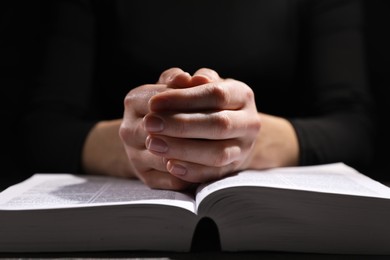 Religion. Christian woman praying over Bible at table, closeup
