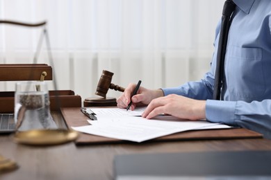 Photo of Lawyer working with documents at wooden table indoors, closeup